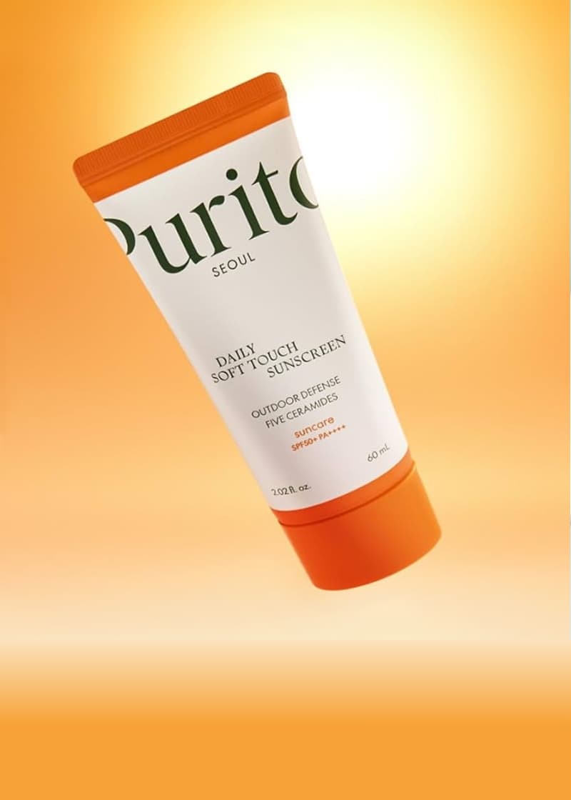 Purito sunscreen tube on an orange gradient background