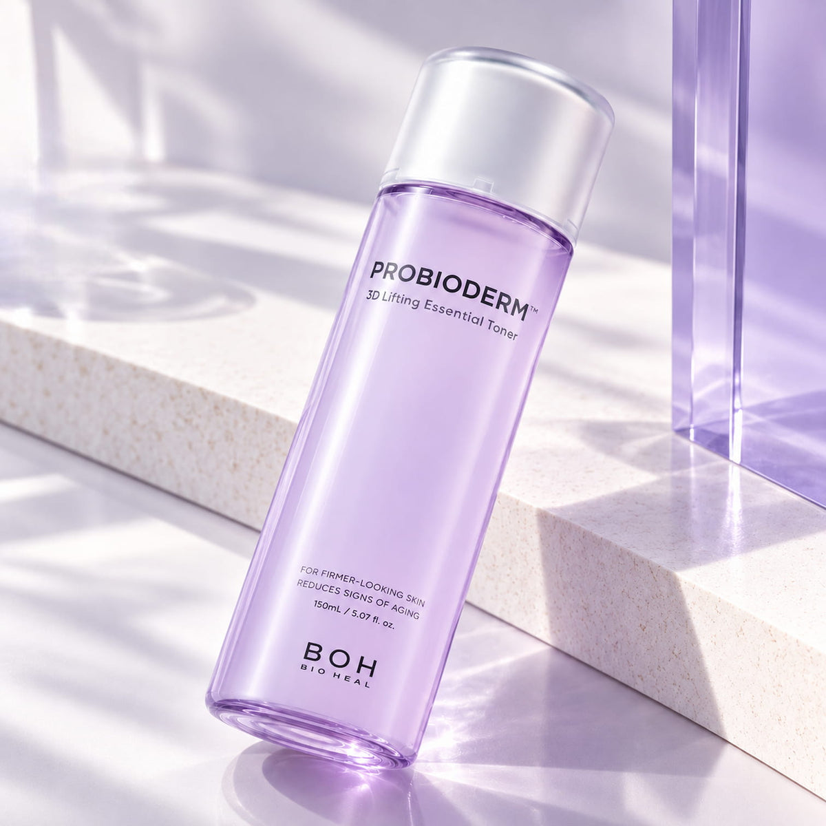 A 150ml bottle of BIOHEAL BOH Probioderm 3D Lifting Essential Toner, featuring a translucent lavender-purple body and a metallic silver cap, set on a modern light beige stone platform with soft shadows.