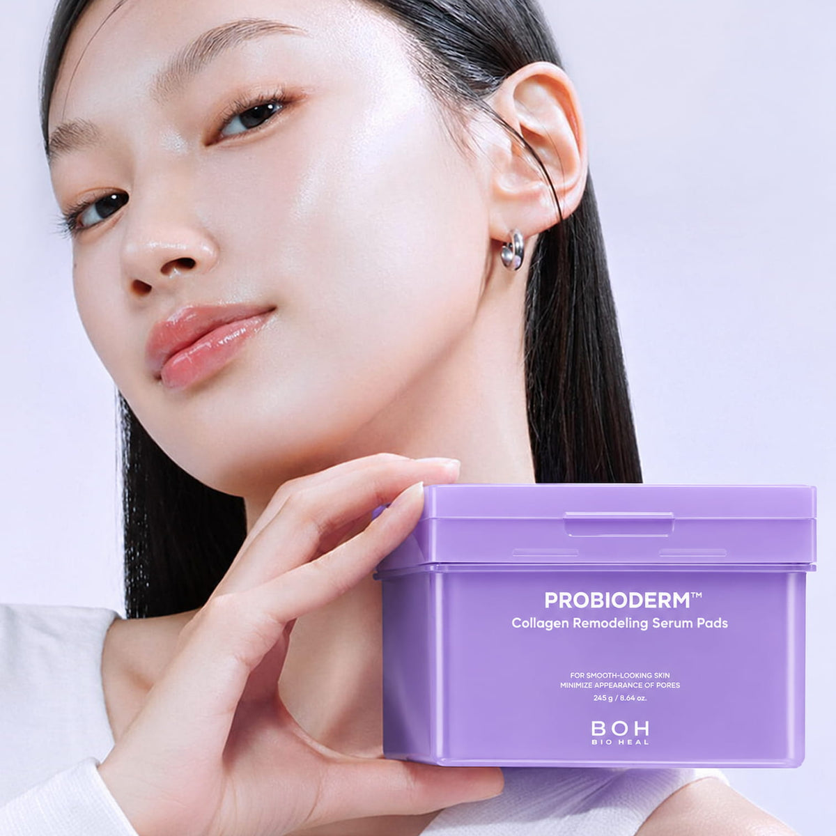 A woman holds a lavender purple tub of BIOHEAL BOH Probioderm Collagen Remodeling Serum Pads against a clean light background.