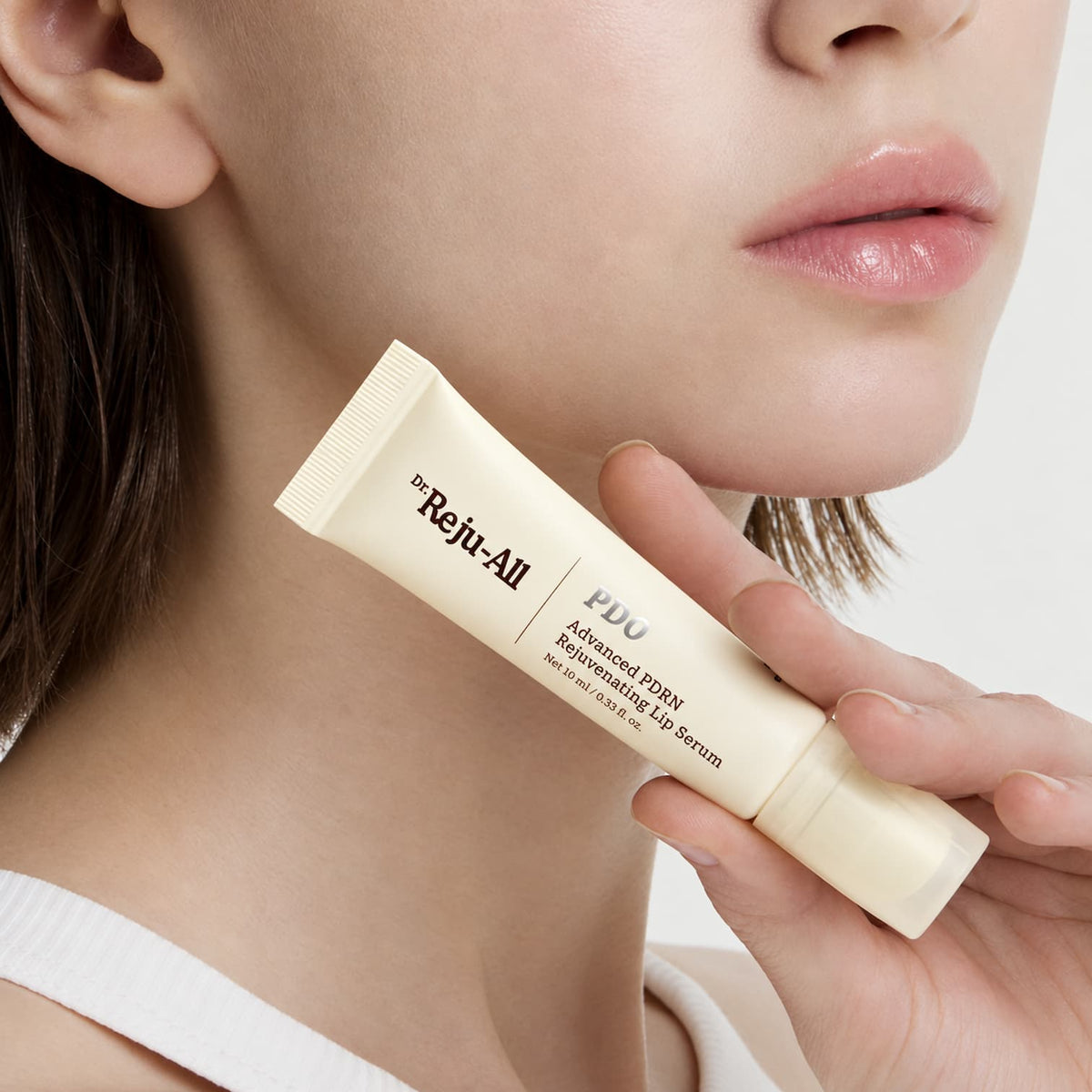A close-up of a lady holding a tube of Dr.Reju-All Advanced PDRN Rejuvenating Lip Serum 10ml against a clean white background.