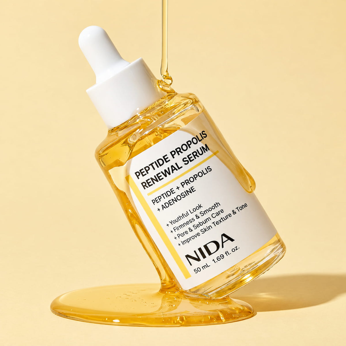 A clear glass dropper bottle of NIDA Peptide Propolis Renewal Serum filled with golden yellow liquid, set against a warm beige background with a gold liquid drip above and below the bottle.