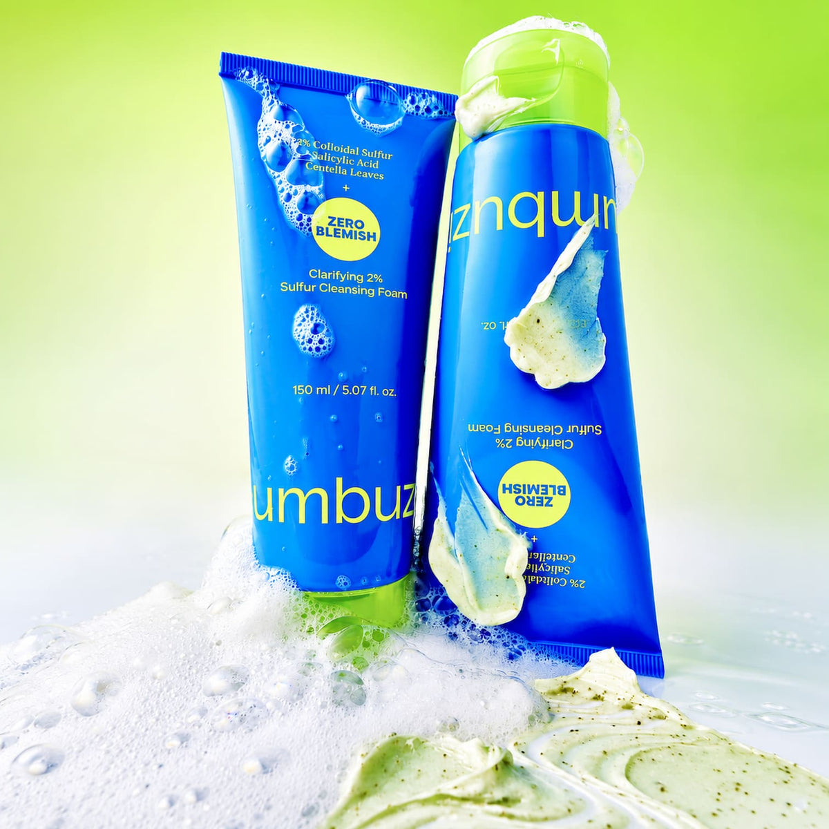Two tubes of NUMBUZIN No.0 Zero Blemish Clarifying 2% Sulfur Cleansing Foam standing in foamy water against a bright green gradient background.