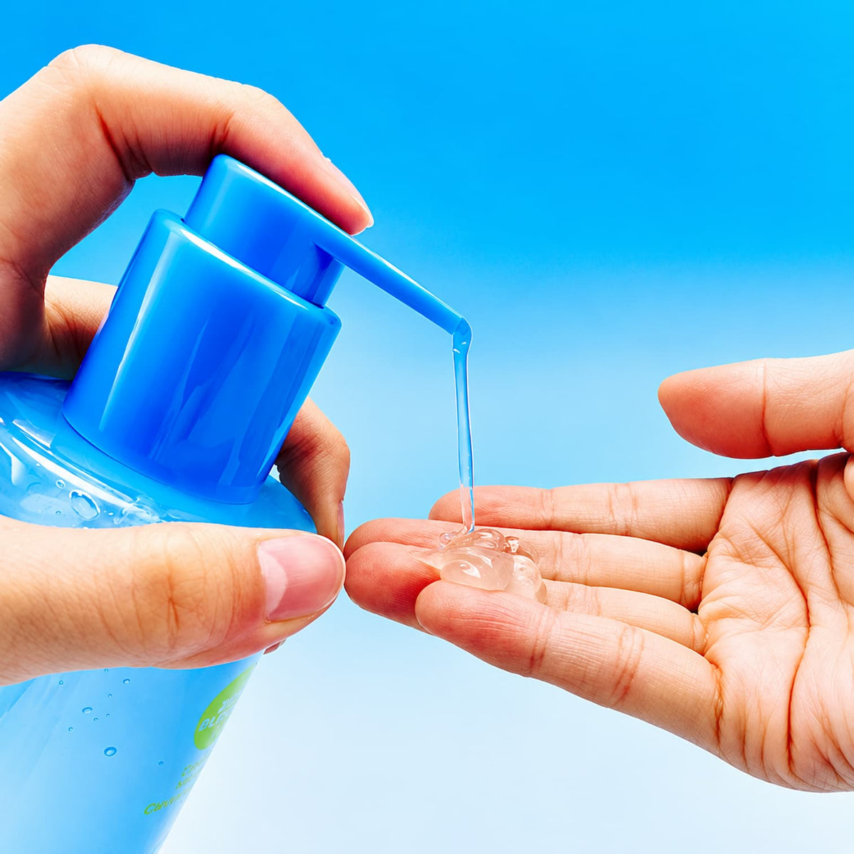 A close-up of a person's hands dispensing cleansing gel from a bright blue pump bottle into another hand, set against a solid blue gradient background.
