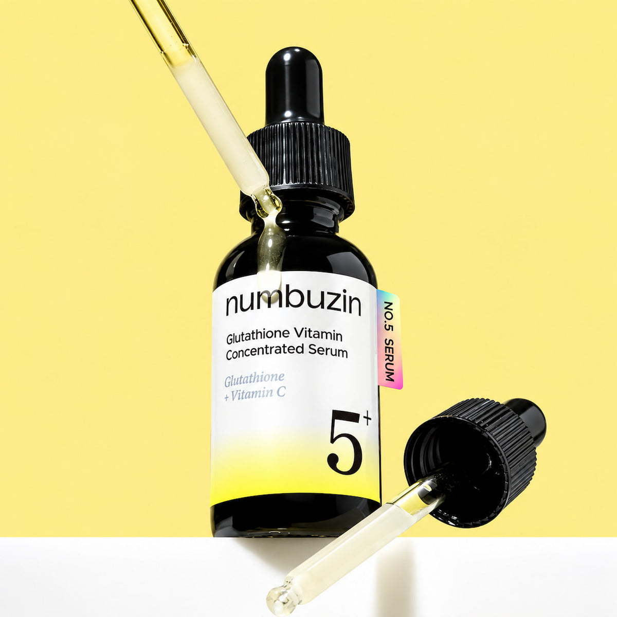 A bottle of numbuzin Glutathione Vitamin Concentrated Serum with a black dropper cap, shown with one dropper filled with pale yellow serum and another lying on its side against a pale yellow background.