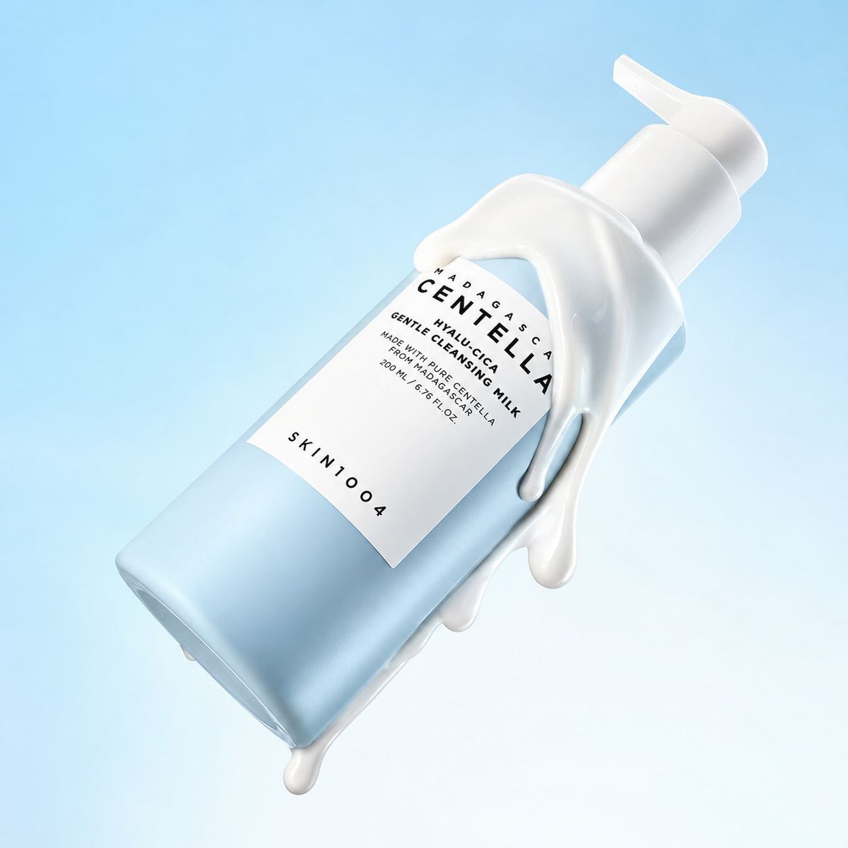 A 200 mL bottle of SKIN1004 Madagascar Centella Hyalu-Cica Gentle Cleansing Milk, shown at an angle with white cream dripping from the pump and bottle against a light blue gradient background.