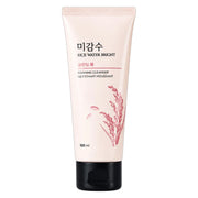 A 100 ml squeeze tube of Rice Water Bright Foaming Cleanser, featuring a pale pink body with a black flip-top cap and a pink rice plant illustration, set against a plain white background.